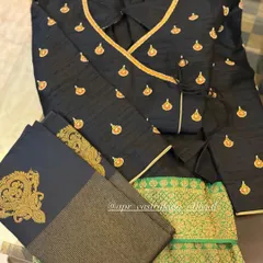 A stylish angrakha-style wrap blouse in black, featuring gold butti embroidery and piping. It is paired with a green brocade skirt for a chic, modern ethnic look.