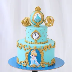 A fairytale Cinderella cake that is pure magic. This two-tiered blue cake is adorned with ornate gold details, a clock striking midnight, and Cinderella's pumpkin carriage as a topper.