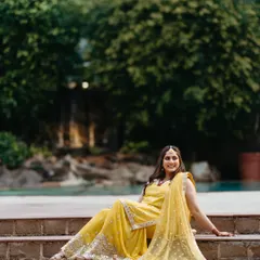 A relaxed and happy portrait of the bride during her mehndi ceremony. Seated on the steps, her yellow outfit glows, and her smile is infectious.