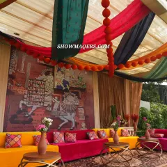A vibrant lounge area from our 'Banarasia' themed Mehendi. We used colorful seating in fuschia and yellow, a traditional Persian rug, and a backdrop of Banaras art to create a lively and cultural atmosphere.