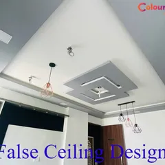 A contemporary living room ceiling with a layered, offset square design in grey and white. The structure is prepared for the installation of multiple pendant lights and includes integrated speakers for a complete media experience.