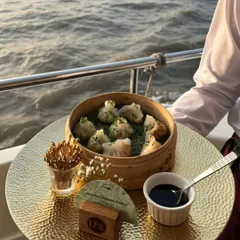 A server presenting a bamboo steamer of assorted dim sum during a yacht party. We ensure that even on a moving boat, the food is fresh, hot, and beautifully presented.
