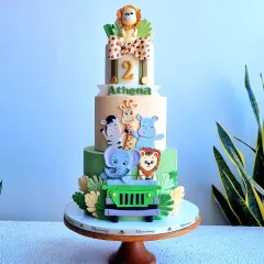 A grand three-tier safari adventure cake, perfect for a milestone birthday. This design features a whole crew of friendly, handmade fondant animals like a lion, elephant, and giraffe in a jeep, set against a backdrop of fondant leaves, creating a fun jungle expedition theme.