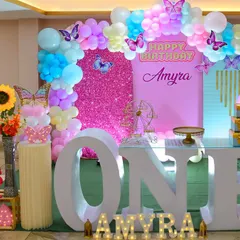 A stunning butterfly-themed first birthday setup, showcasing the grand "ONE" sign and beautiful balloon arch.