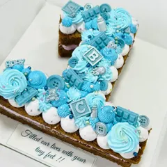 A beautiful number '1' monogram cake for a baby girl's first birthday. The blue theme is accented with edible baby blocks, buttons, and chocolate bars.