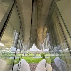 Looking through the layers of glass and metal at the Bocconi campus. The design creates a complex visual depth, blurring the boundary between the interior and the landscaped courtyard.