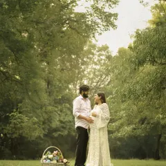 A classic, romantic portrait of a couple standing in a beautiful green park. The natural surroundings create a timeless and serene atmosphere.