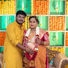 A couple poses for a portrait during their traditional baby shower ceremony, surrounded by marigold flower decorations. We are experienced in respectfully documenting traditional family functions.