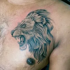 The finished lion head chest tattoo. The focus is on the intense expression and the flow of the mane, creating a powerful and realistic animal portrait.