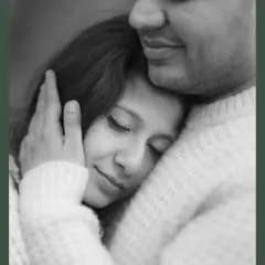 A close-up black and white portrait showing Sayantani resting peacefully in Piyush's embrace. This image conveys a profound sense of safety, comfort, and trust.