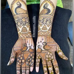 This design is filled with classic motifs. It features majestic peacocks on both the palms and forearms, complemented by delicate hanging jhumka (earring) elements.