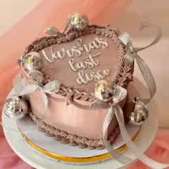 A fun and glamorous heart-shaped cake for a bachelorette party. This "last disco" cake has a shimmery mauve finish, chocolate piping, and is decorated with mini disco balls and silver ribbons.