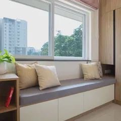 This cozy window seat in a guest room provides comfortable seating and includes built-in storage underneath. It is a practical way to add function to a small space while creating a perfect spot to relax.