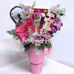 This unique gift is a bouquet of goodies arranged inside a large pink tumbler. It's a creative and modern alternative to a traditional flower bouquet, filled with makeup, accessories, and treats.