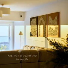 Warmth and tranquility define the living area. The evening sun highlights the texture of the custom artwork and the soft, tufted sofa, creating an ambiance perfect for relaxation. Every corner is designed to feel smooth and inviting.