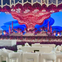 For a celebration that demands drama and vibrancy, we craft scenes of unparalleled scale. This outdoor stage features a massive, sculptural floral canopy in bold reds and purples, set against a custom digital backdrop for a truly surreal experience. 💜