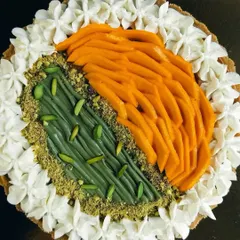 A top-down view of the Half & Half Mango Pistachio tart, showing the beautiful contrast between the orange mango slices and the green pistachio cream.