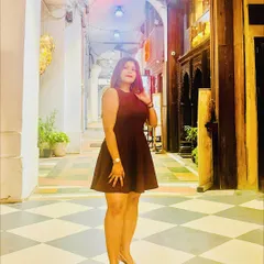 Posing in a beautiful arched hallway. This classic maroon skater dress is a versatile piece that can be dressed up or down, making it a valuable addition to any wardrobe.
