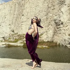 A wide shot of the Siren character in her element by the water, showing how the makeup and styling work with the environment.