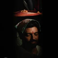 An artistic and moody portrait of the groom during a wedding ritual. The low-key lighting creates a sense of solemnity and introspection, highlighting the importance of the ceremony.