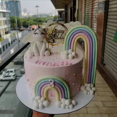 A sweet and simple unicorn cake with a pastel rainbow and fluffy clouds. The design features a cute fondant unicorn sitting on a pink cake, perfect for a magical birthday.