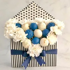 A creative cake pop bouquet arranged in a stylish striped box with fresh carnations. This is a unique and beautiful way to present party favors for a baby shower or birthday.