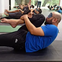 A student practices a blindfolded core exercise. This challenges their balance and proprioception, forcing them to rely on internal cues rather than sight.