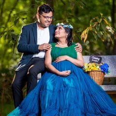 A simple park bench becomes the perfect spot for a loving portrait. The expecting mother looks stunning in a blue gown, and the "Coming Soon" sign adds a sweet, personal touch to their photo.