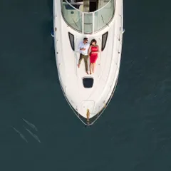 An overhead drone shot shows a couple relaxing on the bow of a luxury yacht in the middle of the deep blue sea. This type of pre-wedding shoot in Goa offers a unique and adventurous experience.