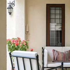 A closer look at the comfortable seating on the outdoor deck. The white cushions provide a crisp contrast to the black metal frames, while a colorful kilim-style pillow adds a touch of pattern and warmth.