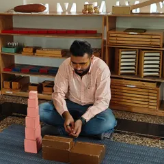 A father deeply focused on the iconic Montessori Pink Tower. In our Silent Journey workshops, parents work with the materials themselves to gain a profound, first hand understanding of their child's world of learning.