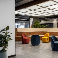 This breakout area in the Clayworks office features colorful, modern furniture under an artificial skylight. It’s a space designed for informal meetings and creative brainstorming.