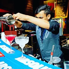 The art of the pour is central to what we do. This shot captures one of our mixologists carefully crafting a vibrant cocktail, showcasing the precision and attention to detail that goes into every single drink we serve.