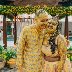 A happy couple covered in turmeric paste during their Haldi, sharing a laugh. Our courtyards are perfect for such fun-filled events.