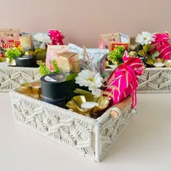 Our macrame trays offer a bohemian and stylish alternative to traditional boxes. This hamper is filled with goodies and decorated with a bright pink potli.
