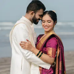 The beauty of a shared smile. This candidly styled portrait captures a moment of genuine happiness and comfort between the couple, set against the soft light of the beach.