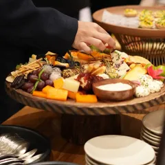 A guest helps themselves to our artisanal cheese and charcuterie board. We design our grazing tables to be interactive and inviting, encouraging guests to explore and enjoy.