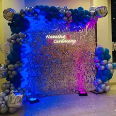 A closer look at the naming ceremony sequin wall with blue and pink lighting. The shifting lights create a dynamic and fun effect.