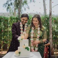 A happy couple cutting their cake at an outdoor engagement, framed by a curtain of hanging flowers.