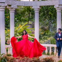 A moment of pure joy and movement. The bride-to-be twirls in her magnificent red gown at the classic white pillar setup, creating a dynamic and happy pre-wedding portrait.