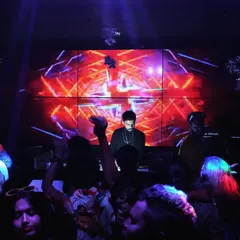At the heart of my setup is the visual experience. Here I am at the console, surrounded by the crowd, with a massive LED wall displaying custom VJ graphics that sync perfectly with the EDM and bass house tracks.