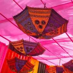 A view looking up at the decorative umbrellas and pink fabric ceiling, a key feature of the GIVA Holi event decor.