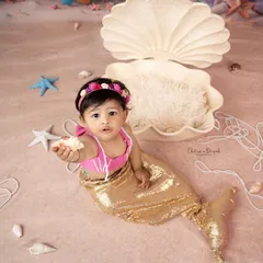 A charming shot of our little mermaid offering a seashell, set against a backdrop of pearls and starfish in our studio.