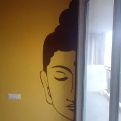 A creative placement of a large Buddha face decal, partially revealed from behind a sliding door on a warm yellow wall.