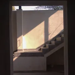 A framed view of the same staircase, seen through a doorway. The composition captures the abstract quality of light and shadow, turning a functional element into a piece of art.