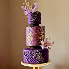 Inspired by the timeless beauty of a Banarasi saree, this three-tiered anniversary cake is a tribute to Indian artistry. The design features deep purple fondant with intricate gold stenciling, monochrome ruffles, and delicate wafer paper flowers. It’s a luxurious and unique creation for a truly special celebration.