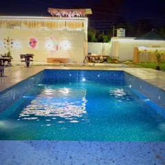 A clean, serene view of the swimming pool at night. The underwater lights and surrounding decor make it an inviting centerpiece for any party.