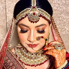 A close-up of a stunning bridal makeup look I created. I focused on a warm, golden-bronze eye with dramatic lashes and a perfectly defined lip to complement her traditional red bridal attire and jewelry. Notice the matching red nails.