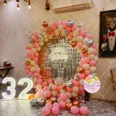 A stylish 32nd birthday party with a pink, cream, and rose gold balloon ring, a shimmer backdrop, and a marquee number '32'.