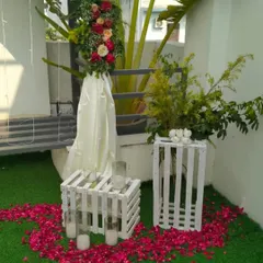 A daytime view of the decorative elements, including white wooden crates used as tables, candles, and floral arrangements on a green turf.